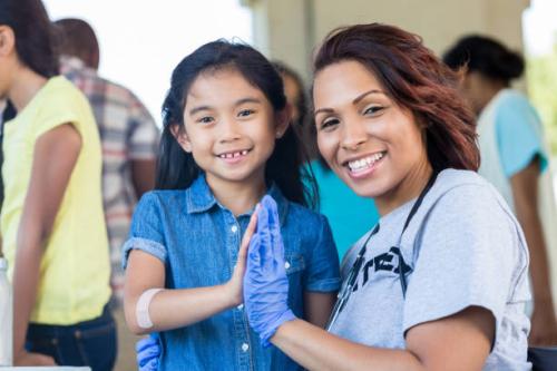 Young patient and female doctor high five during a free community health fair.